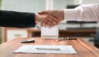 A photo of two people shaking hands over a signed document