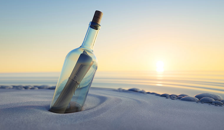 A picture of a bottle with a message on a beach