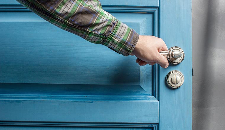 A photo of a man closing a blue door