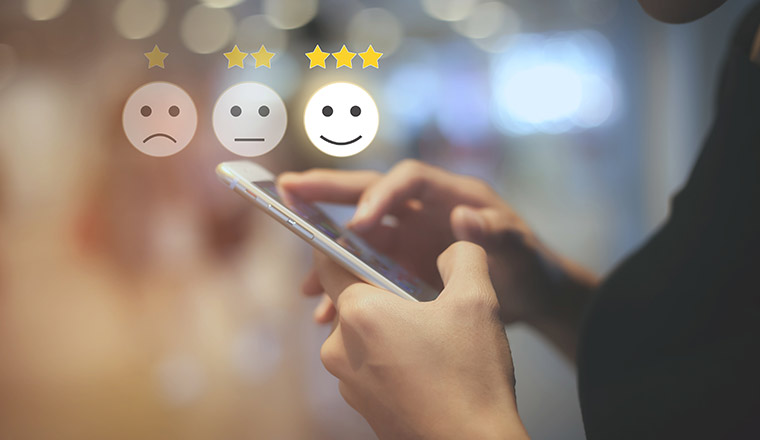 A person on a phone selects a happy face with 3 stars