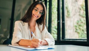 A happy woman writes on a clip board