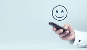 A photo of a smiley emoji above a mobile phone