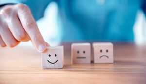 A person moves a wooden cube with a smiley face