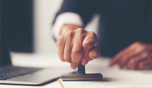 A man in a suit stamps documents in assurance