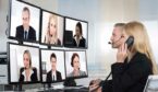 A woman on the phone talks to a group of people on different monitors