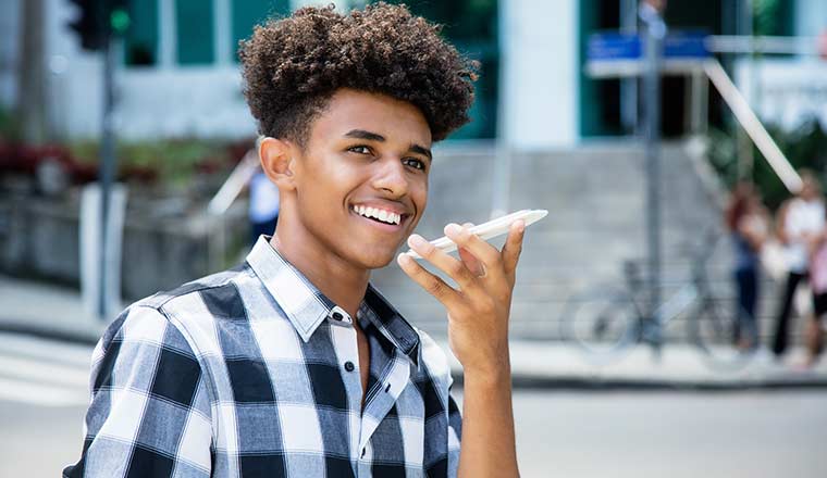 A young man talks into his smart phone