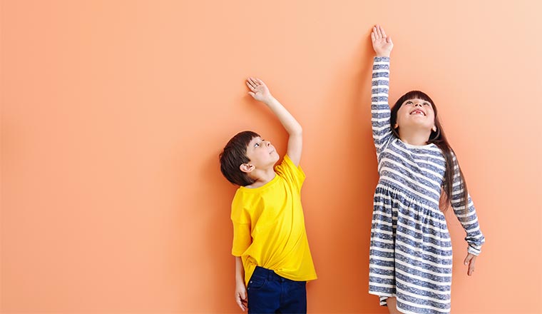 A photo of children reaching to measure