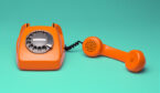 An orange old fashioned telephone