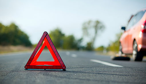 A photo of a red triangular sign next to a car puncture