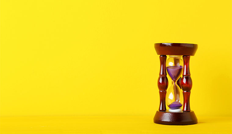 A photo of an hourglass on a yellow background