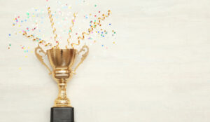A golden cup has confetti exploding out of it