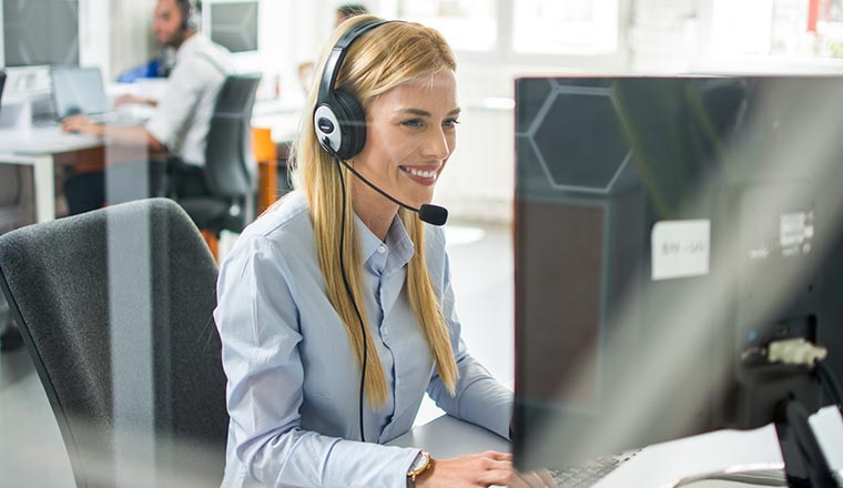 A happy contact centre advisor sits in front of a computer screen