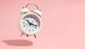 An alarm clock showing 20 past ten on a pink background