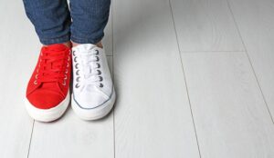 A person wearing jeans and a red shoe and a white shoe
