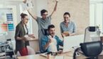 A photo of a happy team gathered around a computer