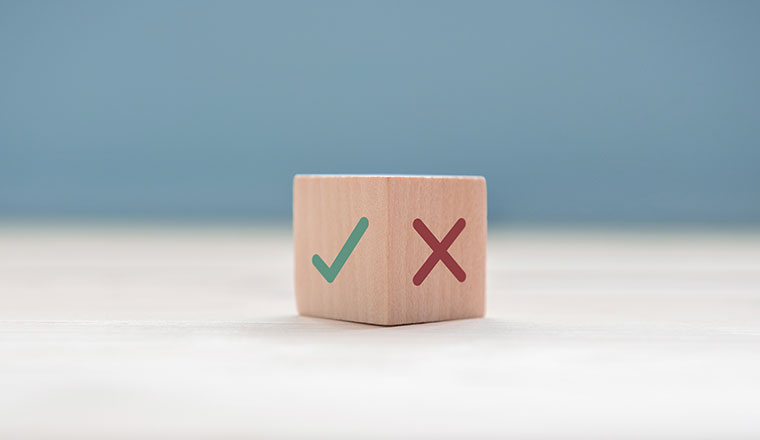 A photo of a wooden block with a tick and a cross