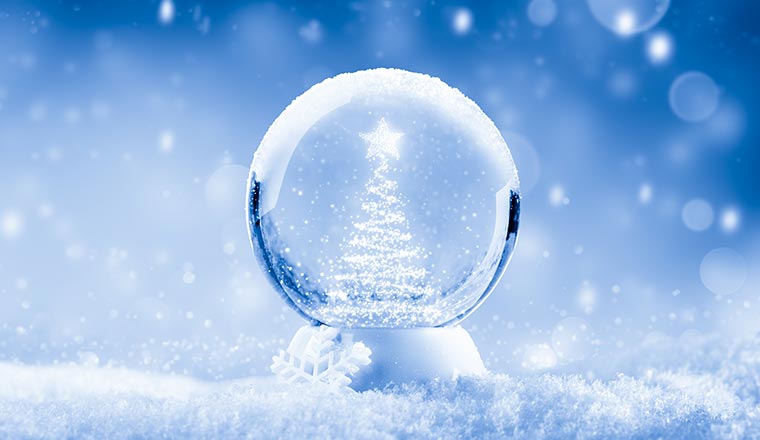 A snow globe on a blue background with a snowy Christmas tree shape inside