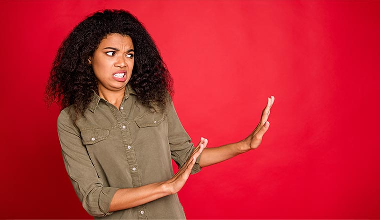 A woman pushes her hands away from her, with a worried look on her face