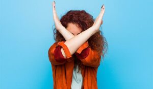 A woman holds her hands across her face