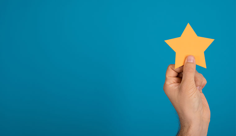 A photo of someone holding a yellow star against a blue background