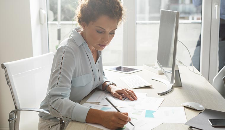 A photo of someone making notes at a computer