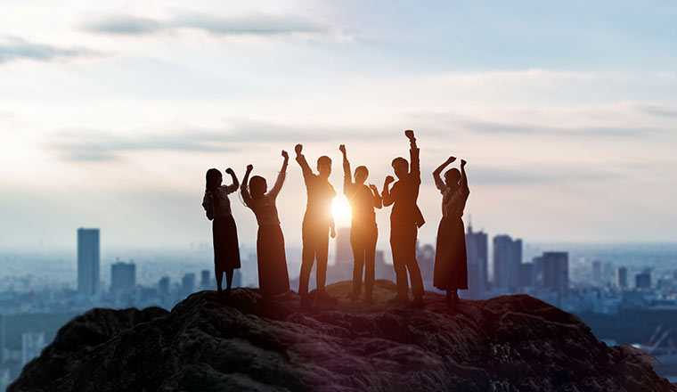 A picture of a group of people on a mountain overlooking a skyline