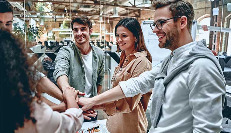 A photo of an office team putting their hands together