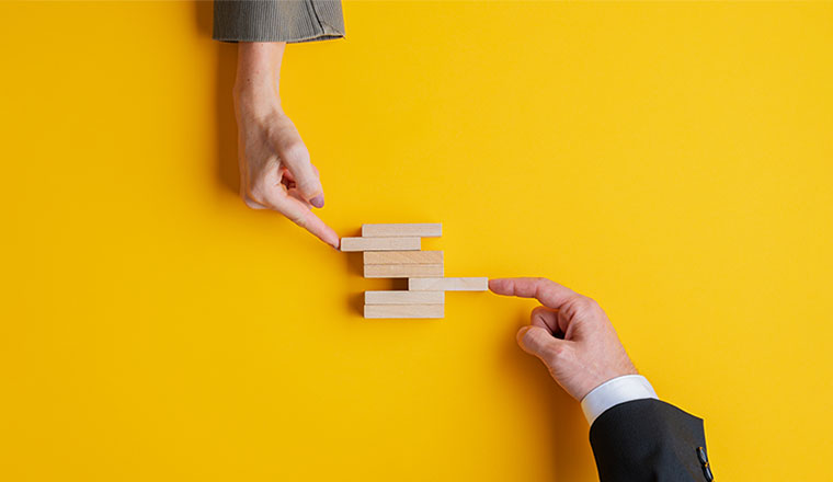 A photo of two hands building a jenga tower