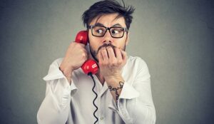 A picture of a person looking nervous on the telephone