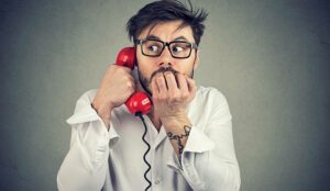 A picture of a person looking nervous on the telephone