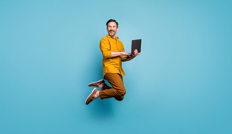 A photo of someone jumping in the air with a laptop