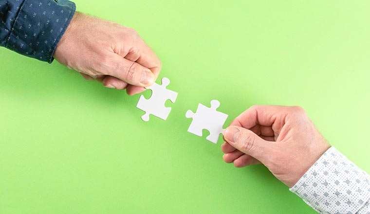 A photo of two people connecting puzzel pieces