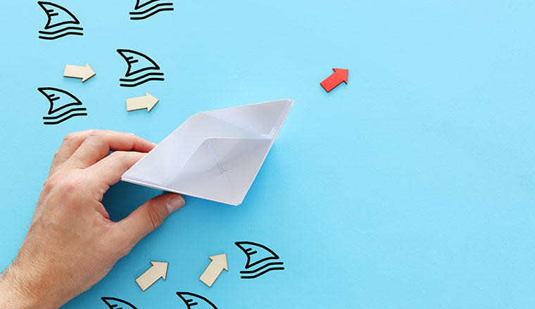 A picture of a paper boat avoiding shark fins