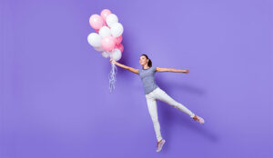 A photo of an engaged staff member being carried away by balloons