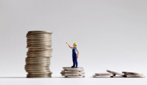 A picture a large stack of coins with a miniature worker