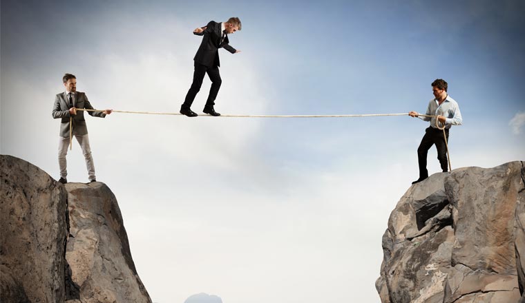 A picture of an agent walking across a rope supported by colleagues