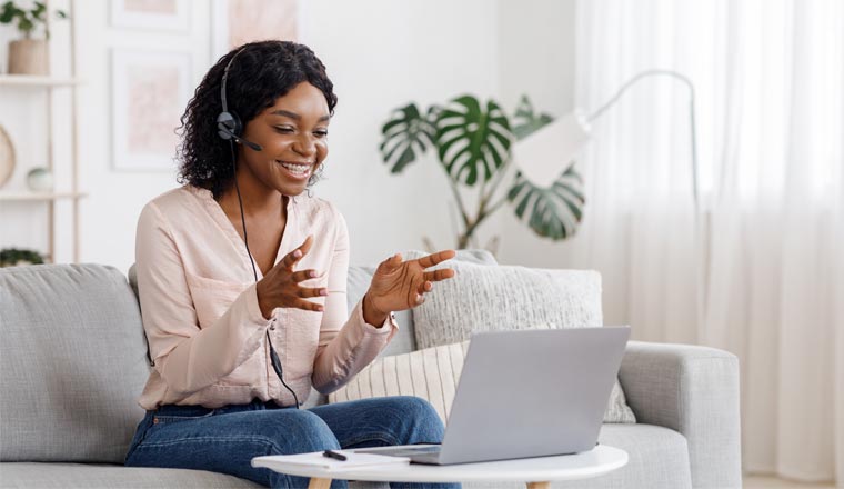 A picture of an agent working at home with a headset and laptop