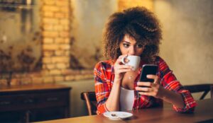 A picture of a customer looking at mobile-phone and drinking coffee
