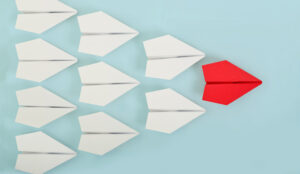 A picture of a red paper boat leading a group of boats