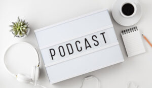 A picture of Podcast word on lightbox with headphones on white table
