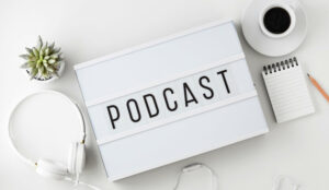 A picture of Podcast word on lightbox with headphones on white table