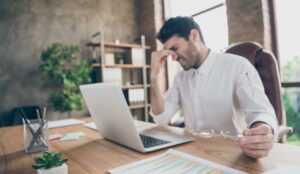 A picture of an agent holding head at desk