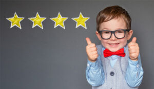 A picture of a young boy holding up his thumbs with four stars