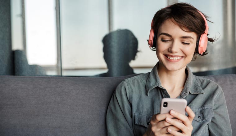 A picture of a lady wearing headphones and listening to a podcast on mobile