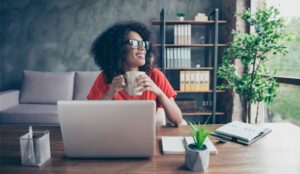 A picture of a remote worker sat at desk with a cup of coffee