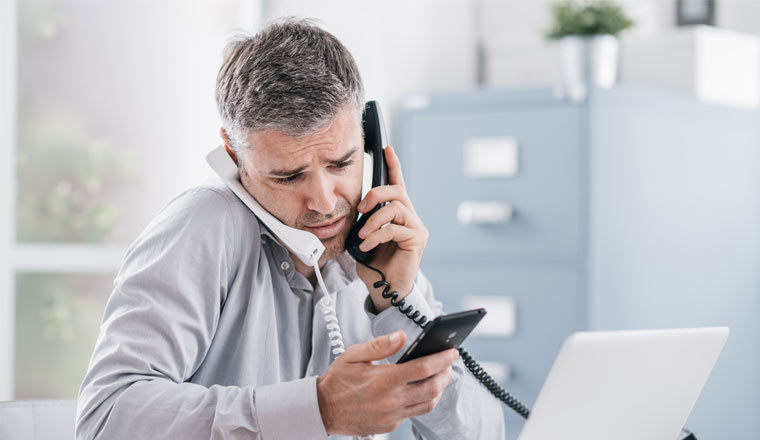 A picture of a stressed agent holding three phones