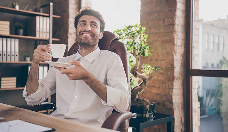 A picture of a man sipping tea in an office