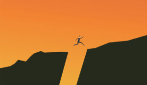 A picture of a person jumping over a gap between rocks