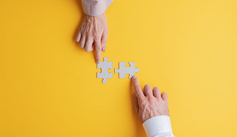 A photo of people pushing puzzle pieces together