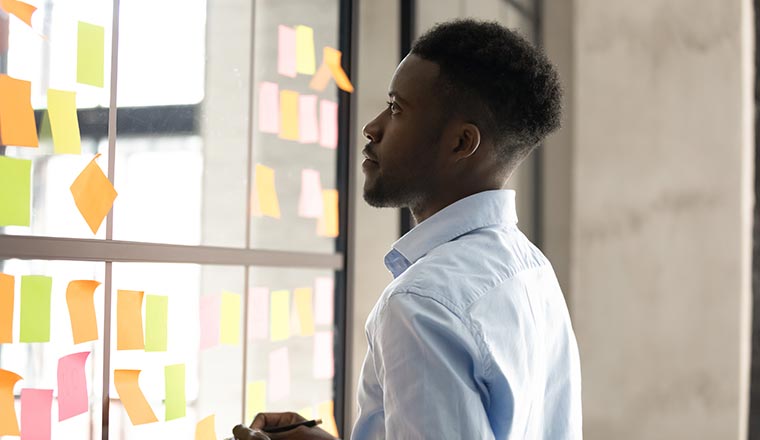 A photo of a man staring at a post-it board